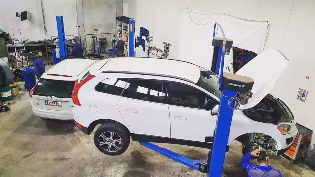 Beli Volvo XC60 na dizalici u našoj radionici, serviseri rade na vozilima